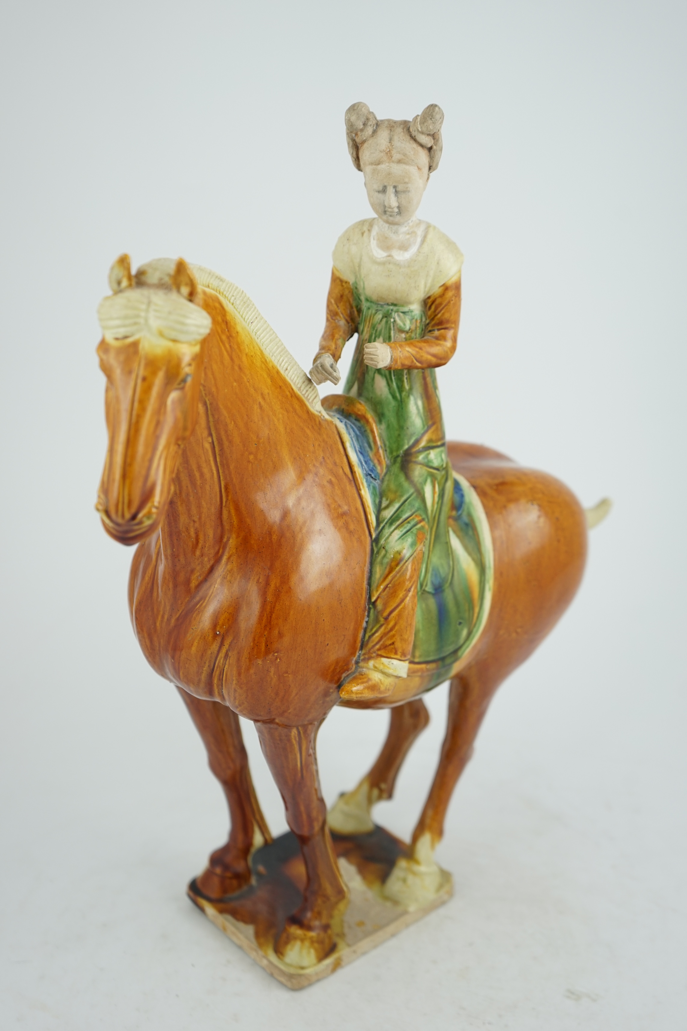 A Chinese sancai glazed group of a horse and female rider, Tang or later